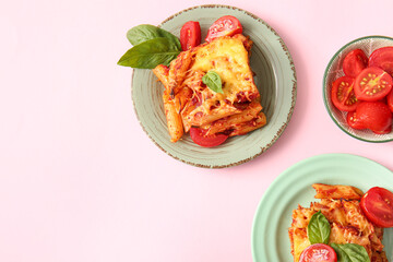 Plates of pasta with tomato sauce and cheese on pink background