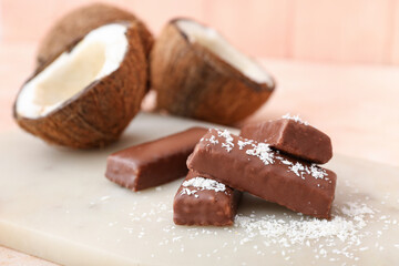 Board with tasty chocolate covered coconut candies on table