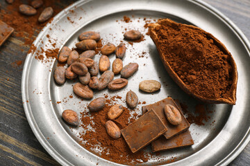 Cocoa pod with powder, beans and chocolate on wooden background