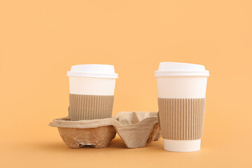 Takeaway paper cups with holder on beige background