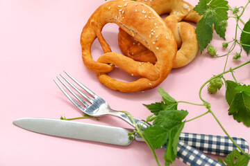 Soft pretzels with cutlery on pink background