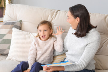 Cute little girl showing her drawing to beautiful mother at home