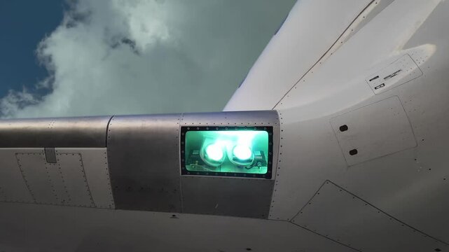 External close-up view of the landing lights of white color fuselage jet selected on while flying under some stormy white clouds. 4K 60FPS