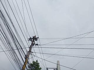Display of power cables and internet network cables attached to electric poles against a white...