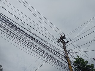 Display of power cables and internet network cables attached to electric poles against a white...