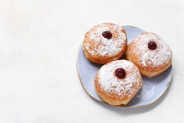 Plate with sweet donuts for Hanukkah celebration on light background