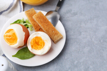 Soft boiled eggs with bread on grey table, closeup. Space for text