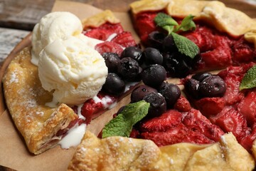 Tasty galette with berries, ice cream and mint on table, closeup