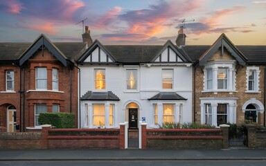 Beautifully lit Victorian terrace houses against a colorful evening sky, emphasizing historic charm and elegance.