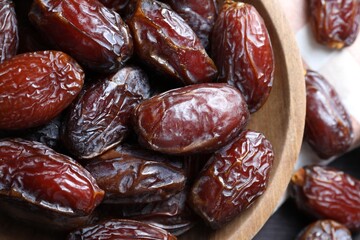 Many tasty dried dates in bowl on table, closeup