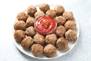 Delicious meatballs with ketchup and spices on light textured table, closeup