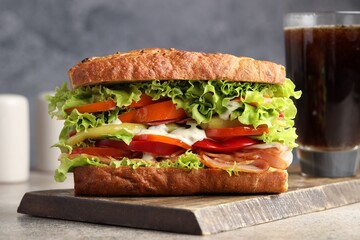 Delicious baguette sandwich with tomatoes and yellow beans on grey textured table, closeup