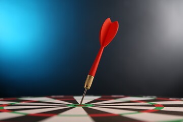 Red arrow hitting target on dart board against blue background, closeup