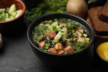 Delicious okroshka soup with kvass and ingredients on black table, closeup