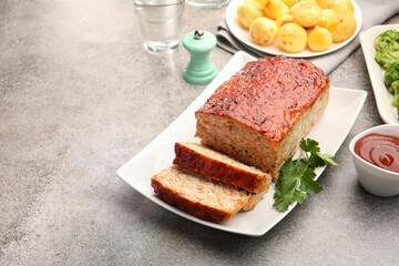 Delicious baked turkey meatloaf with vegetables served on grey table, closeup. Space for text