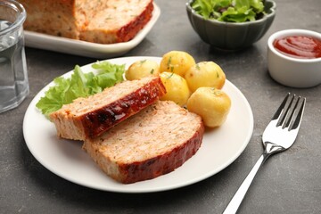 Delicious baked turkey meatloaf with potatoes served on grey table, closeup