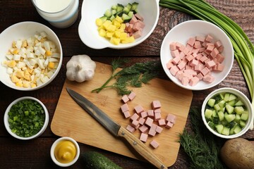 Cut ingredients for okroshka soup and knife on wooden table, flat lay