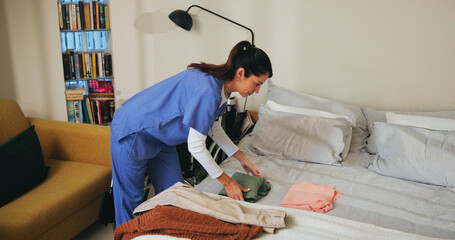 Woman, nurse and fold clothes in home, household tasks and caregiver helping in assisted living....