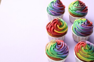 Delicious cupcakes with colorful cream on violet background, closeup. Space for text