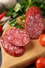 Cut smoked sausage, parsley and tomatoes on black wooden table, closeup