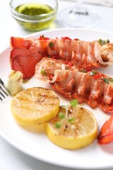 Delicious lobster tails with lemon, microgreens and green onion on white table, closeup