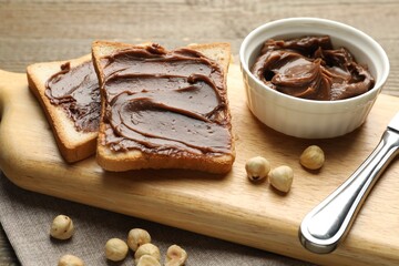 Sandwiches with chocolate butter, hazelnuts and knife on table, closeup