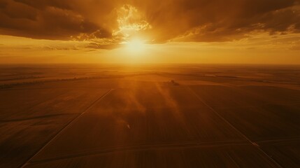 A serene sunset over expansive fields, casting warm golden hues across the landscape.