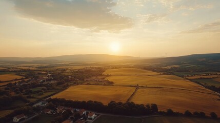 Aerial view of a serene landscape at sunset, showcasing fields and distant hills.