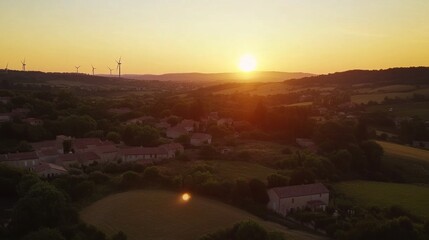 A serene sunset over a rural landscape with wind turbines in the distance.