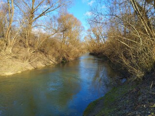 Picturesque landscape. a small clean river in spring with banks overgrown with trees and bushes. Top view of the river with clean transparent water.