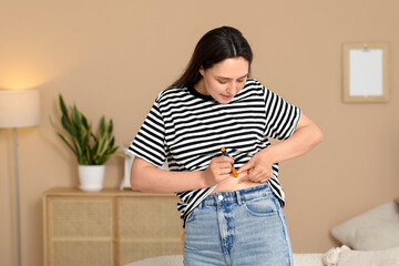 Diabetic young woman using lancet pen at home