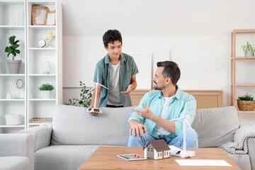 Teenage boy with wind turbine model talking to his father at home