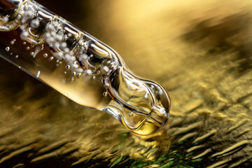 A drop of cosmetic aromatic oil drips from the pipette. Front view.