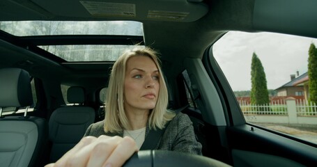 A business woman drives a car around the city on a sunny day. Front view