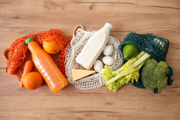 String bags with different fresh products on wooden background