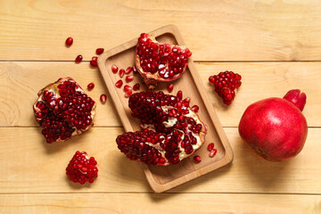 Tray with cut fresh pomegranate and seeds on wooden background