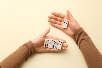 Female hands with dominoes on yellow background, closeup