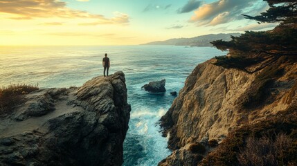 Silhouette of a man standing on a cliff overlooking the ocean at sunset