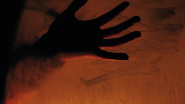Tense shot of a hand silhouette pressing against a glowing car window, evoking despair and finality