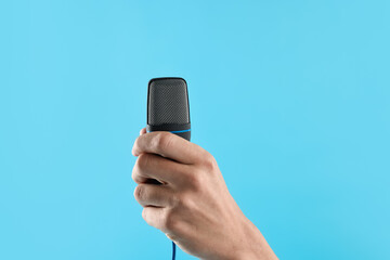 Man with microphone on light blue background, closeup