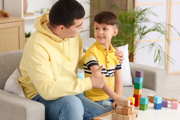 Obraz premium Father hugging his little son with colorful cubes on table at home