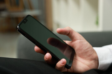 Man using smartphone with blank screen indoors, closeup