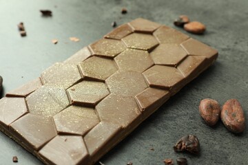 Tasty Dubai chocolate with pistachio, knafeh and cocoa beans on grey textured table, closeup