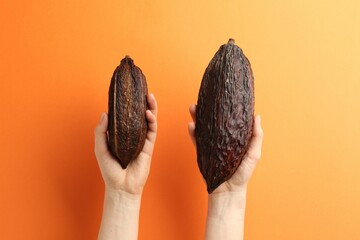 Woman with cocoa pods on orange background, closeup