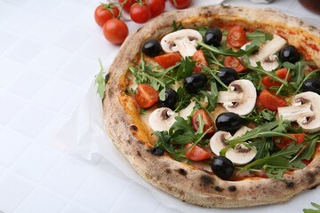 Tasty pizza with cherry tomatoes, black olives, mushrooms and arugula on white tiled table, closeup. Space for text