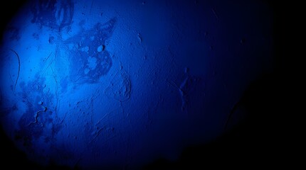 Obraz premium A deep blue light illuminates part of a textured surface, creating an abstract and mysterious atmosphere. Shadows and variations in the blue hues add depth and intrigue.