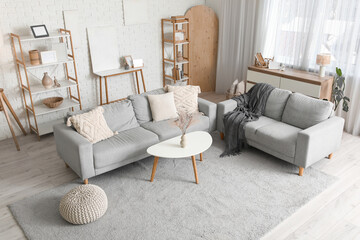Interior of modern living room with grey sofas, table and shelf units