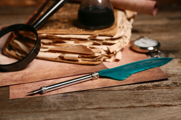 Old book with nib pen, magnifying glass and pocket watch on wooden background