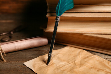 Naklejka premium Old books with nib pen, paper sheet and scroll on wooden background