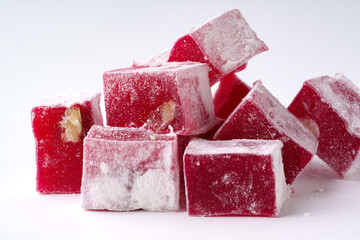 Delightful red Turkish delight cubes dusted with powdered sugar on a white background